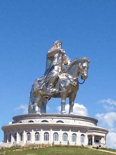 Estatua ecuestre de metal brillante de un líder histórico sobre una base circular.